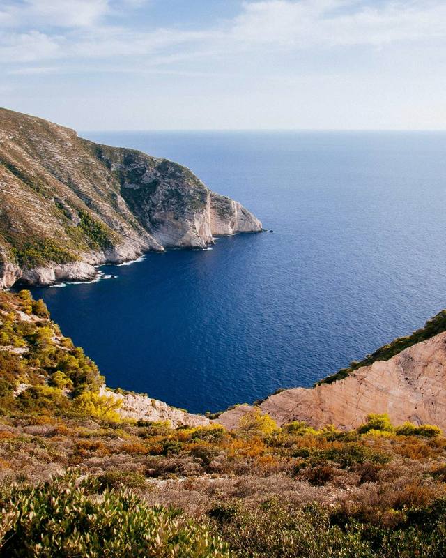 A green cliff above a blue water cove.