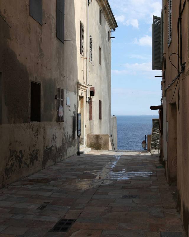A narrow village street with the sea at the end.