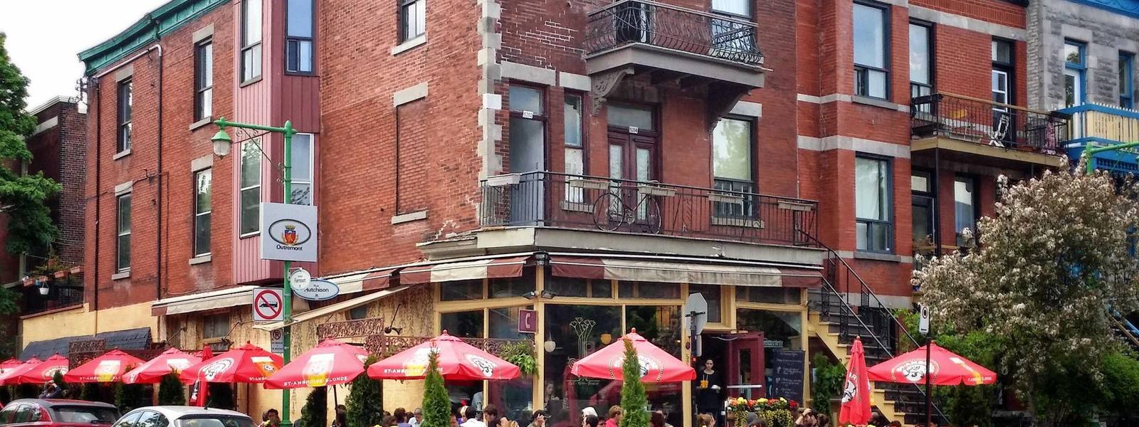 A restaurant terrace with awnings and laid tables along a street.