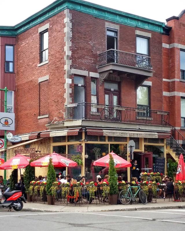 A restaurant terrace with red awnings along a street.