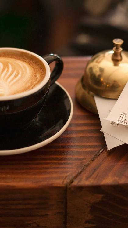 A cup of coffee on the wooden table of a cafe.